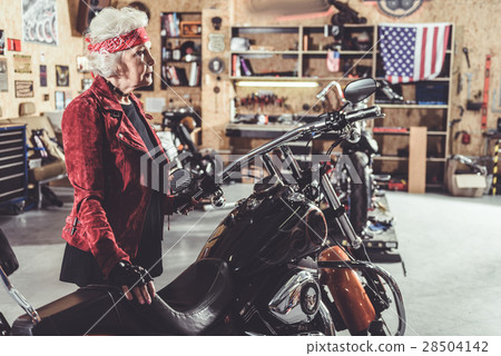 Serene granny situating next to bike in garage Serene granny situating next to bike in garage 28504142