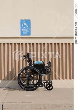 Wheelchir in front of handicapped parking sign Wheelchir in front of handicapped parking sign 28508186