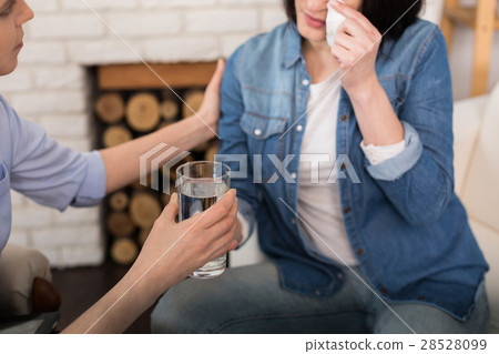 Glass of water being given to a crying woman 28528099