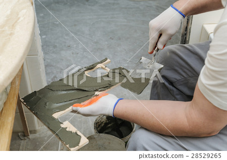 Worker puts the adhesive on the tile. Worker puts the adhesive on the tile. 28529265