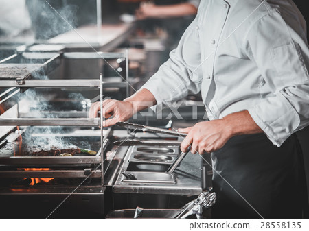 Busy chef at work in the restaurant kitchen Busy chef at work in the restaurant kitchen 28558135