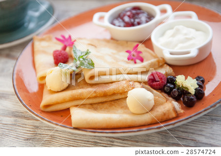 Pancakes with cream and jam and fresh berries on a Pancakes with cream and jam and fresh berries on a 28574724