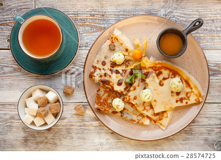 Pancakes on a plate with cream and jam and cup of 28574725