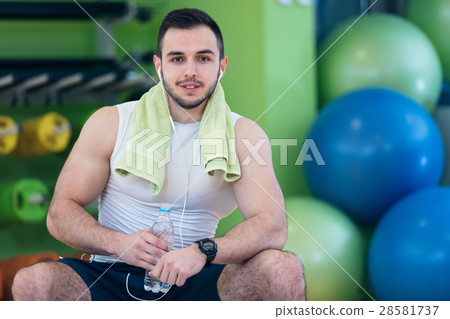 A young man taking a break at the gym sitting on a 28581737