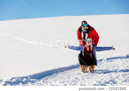 Young playful couple having fun sledging down snow 28581898