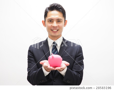 A young businessman with a pink pig's piggy bank A young businessman with a pink pig's piggy bank 28583196