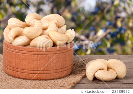 cashew nuts in a wooden bowl on the board with 28589952
