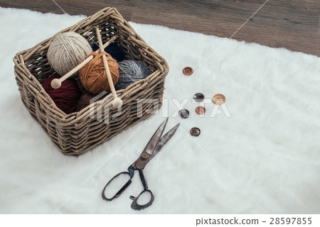 scissors and yarn ball inside old basket on carpet 28597855