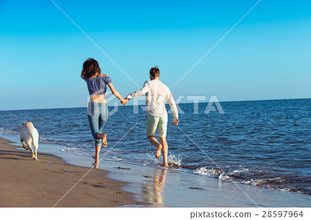 Portrait of a happy couple with dogs at the beach Portrait of a happy couple with dogs at the beach 28597964