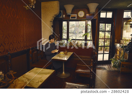 A woman relaxing at a coffee shop 28602428