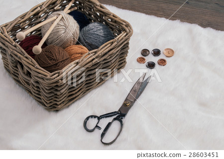 scissors and yarn ball inside old basket on carpet 28603451