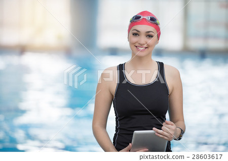 Fit female swimming trainer with tablet at the 28603617