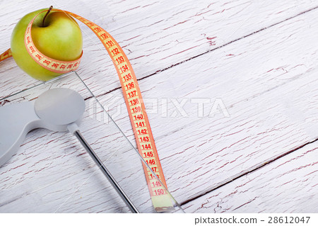 The centimeter stands near a green apple 28612047