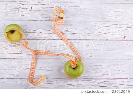 The centimeter stands near  green apples 28612049