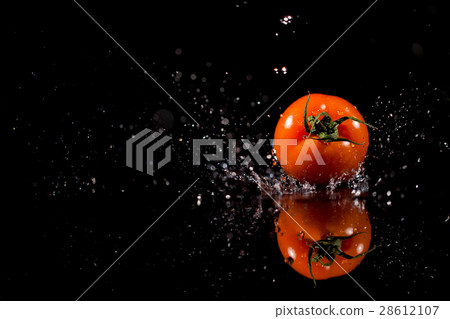 The tomato with drops stands on the black The tomato with drops stands on the black 28612107
