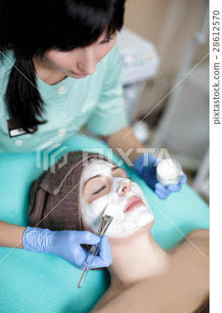 beautician applies face mask on young woman in Spa 28612570