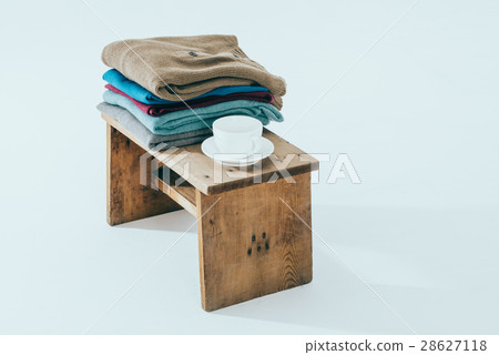 Stack of winter sweaters  and cafe on rustic bench 28627118