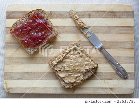 Jam and peanut butter sandwiches on cutting board 28635785