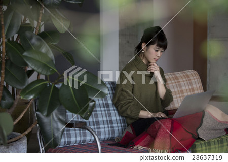 A woman operating a personal computer in a room 28637319