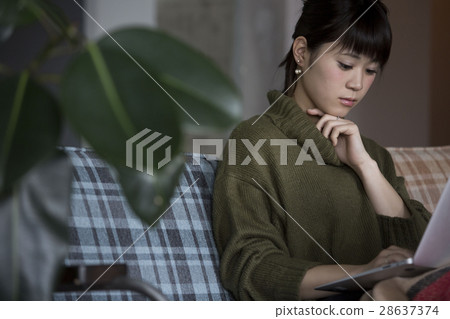 A woman operating a personal computer in a room A woman operating a personal computer in a room 28637374