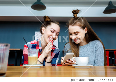 two young beautiful hipster women sitting at cafe 28638353