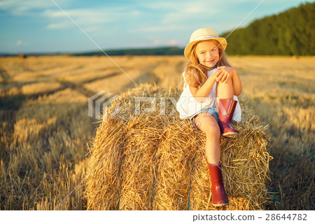 Little girl in a field with hay rolls 28644782