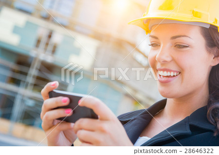 Female Contractor Wearing Hard Hat on Site Texting with Cell Pho Female Contractor Wearing Hard Hat on Site Texting with Cell Pho 28646322