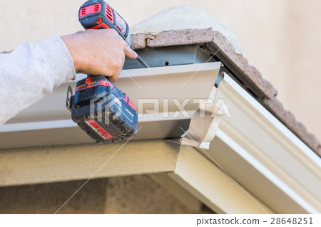 Worker Attaching Aluminum Rain Gutter a House. 28648251
