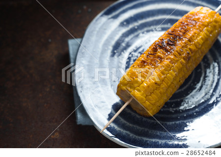 Roasted corn with salt on a blue plate on a metal 28652484