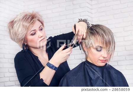 hairdresser makes a hair cut with scissors 28658059