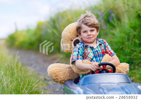 Little kid boy driving big toy car with a bear Little kid boy driving big toy car with a bear 28658932