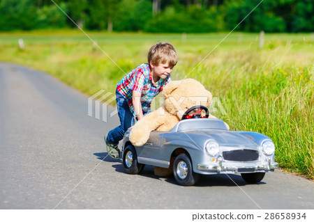 Little kid boy driving big toy car with a bear Little kid boy driving big toy car with a bear 28658934