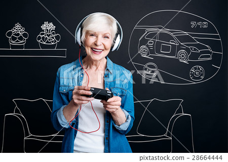 Joyful elderly woman playing video games Joyful elderly woman playing video games 28664444