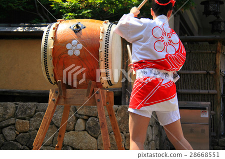 A woman in a coat hitting a drum A woman in a coat hitting a drum 28668551