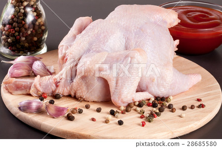 raw chicken carcass with peppercorns on a dark 28685580