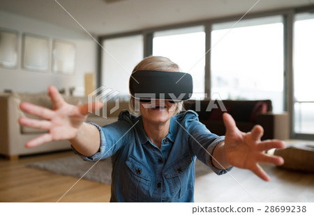 Senior woman wearing virtual reality goggles at 28699238