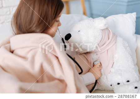 Pleasant little grl examining her fluffy toy Pleasant little grl examining her fluffy toy 28708167