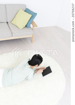 一名控制躺在她的耳朵上的平板電腦的年輕女子躺在她的臉上 一名控制躺在她的耳朵上的平板電腦的年輕女子躺在她的臉上 28708237