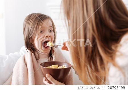 Cheerful nice little girl enjoying breakfast with 28708499