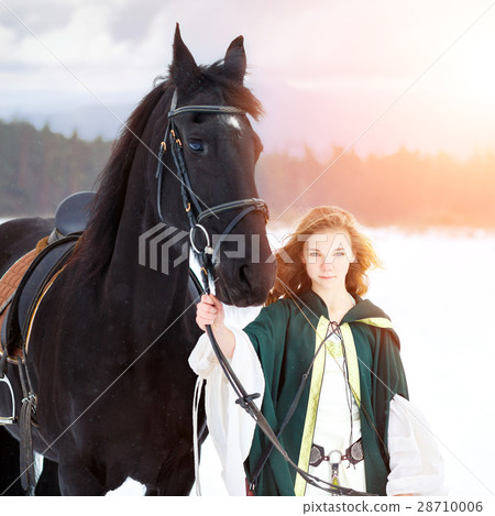 Young girl in dress with black horse in winter Young girl in dress with black horse in winter 28710006