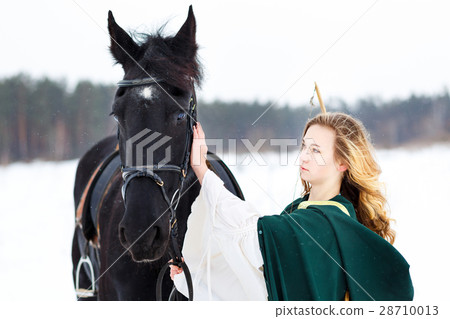 Young girl in dress with black horse in winter Young girl in dress with black horse in winter 28710013