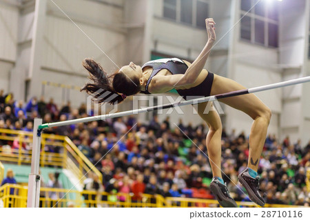 Young girl jumping over bar in high jump contest. 28710116