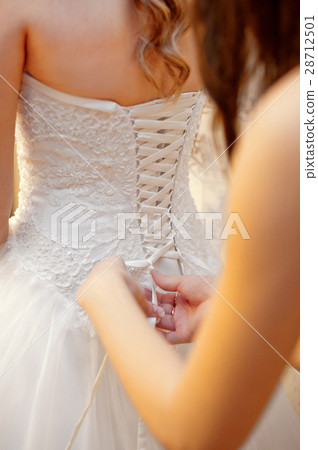 bridesmaid helps the bride to wear dress bridesmaid helps the bride to wear dress 28712501