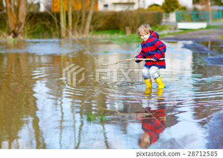 Little child playing with fishing rod by puddle Little child playing with fishing rod by puddle 28712585