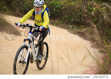 young woman riding mountain bike on forest trail 28728771