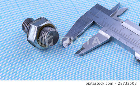 bolt with nut and caliper on engineering paper. bolt with nut and caliper on engineering paper. 28732508