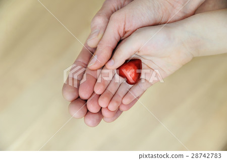 The small red heart is in the hands. 28742783