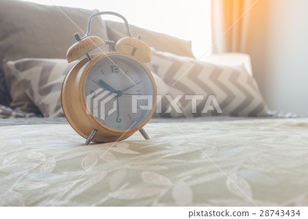 modern alarm clock on bed in bedroom modern alarm clock on bed in bedroom 28743434