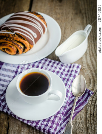 Cup of coffee and poppy bun glazed with ganache 28743823