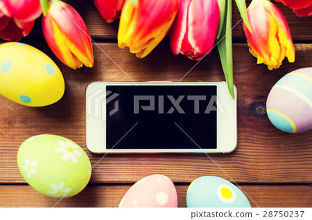 close up of easter eggs, flowers and smartphone 28750237